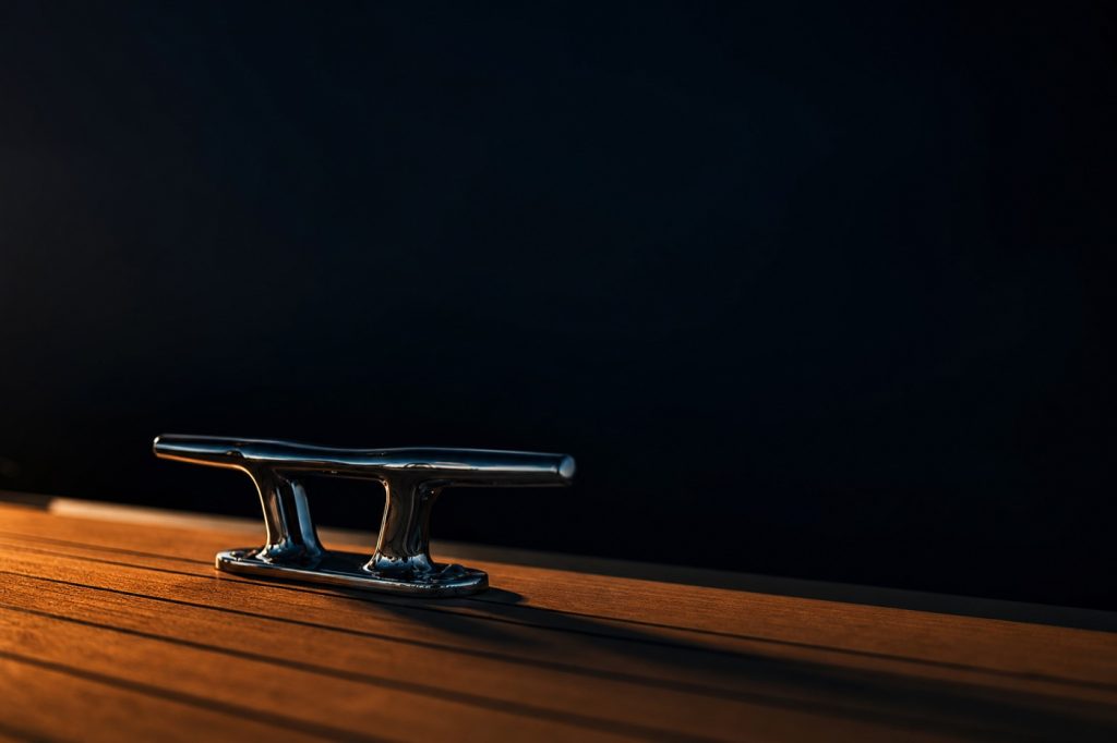 Chrome cleat on teak superyacht deck in warm golden light